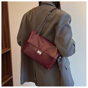 Detail view of burgundy chain shoulder bag with silver turn-lock and metallic strap