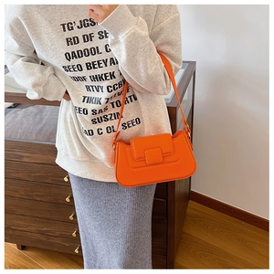 Close-up of bright orange quilted PU leather shoulder bag with a square buckle finish