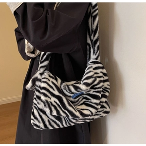 Close-up detail of plush zebra print shoulder bag showing fluffy texture and blue brand label