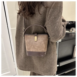 Detail einer minimalistischen zweifarbigen Beuteltasche mit goldenem Drehverschluss und Riemen