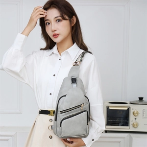 Close-up of grey PU leather sling bag with gold zippers and woven geometric strap