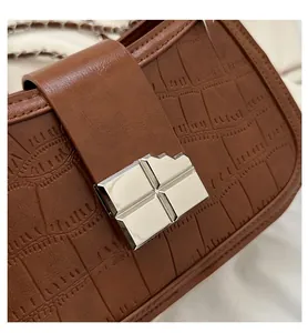 Detailed close-up of dark brown crocodile embossed texture and silver geometric metal lock