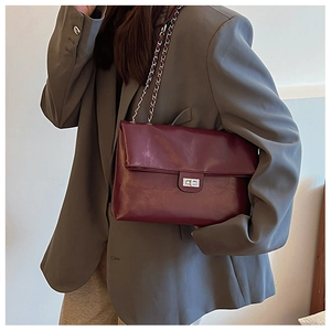 Close-up of a burgundy PU leather shoulder bag featuring a silver metal twist lock closure