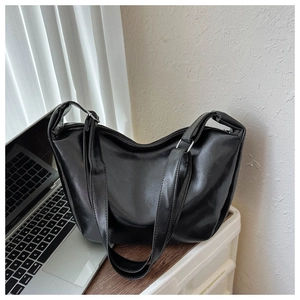 Close-up of flexible black PU leather texture and wide straps on the tote bag