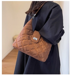 Brown quilted shoulder bag with vintage leather texture worn by a model in a room