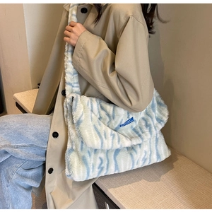 Close-up of plush blue zebra pattern handbag with wide strap worn by model in a trench coat