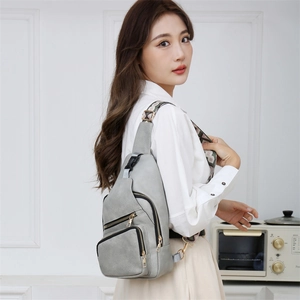Detailed view of a grey PU leather crossbody bag with multiple zippers and wide woven strap
