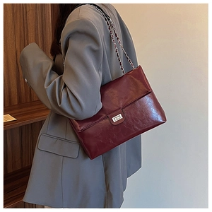 Macro shot of burgundy faux leather texture and silver metal twist lock on shoulder bag