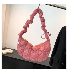 Detail of quilted dusty rose crescent bag with scrunchie strap and bow decoration