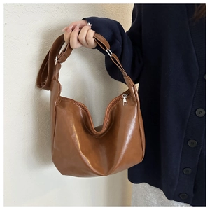 Close-up of caramel brown glossy PU leather hobo bag with silver metallic zipper