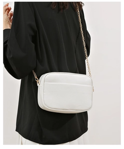 Detailed macro view of white lychee pattern leather shoulder bag with gold chain strap