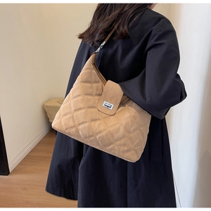 Close-up of beige quilted shoulder bag featuring silver rectangular twist lock closure