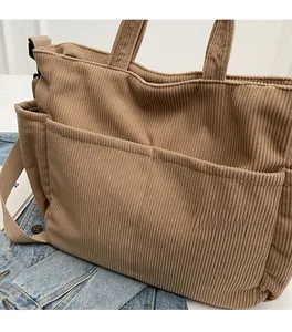 Close-up of tan corduroy tote bag with dual front pockets and adjustable shoulder strap
