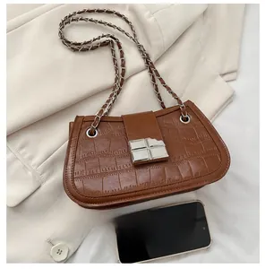 Detail of brown crocodile pattern handbag with silver metal buckle and chain strap
