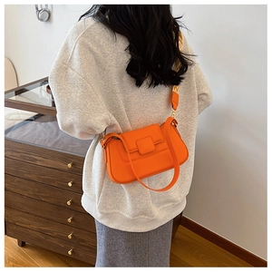 Detail of bright orange rectangular crossbody bag with printed wide shoulder strap
