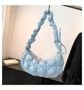 Detail of light blue quilted puffer handbag featuring a ruffled shoulder strap design
