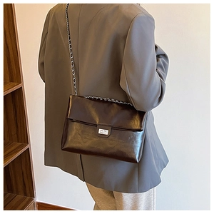 Detailed view of a dark brown PU leather shoulder bag with silver clasp on a model