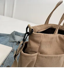 Detail view of corduroy tote bag featuring durable shoulder strap hooks and side pocket
