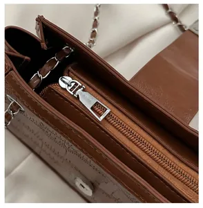 Close-up of smooth silver zipper and embossed leather texture on dark brown bag