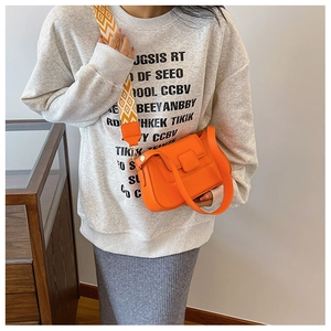 Detail of orange PU leather crossbody bag with a colorful geometric patterned strap