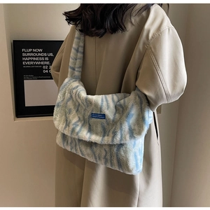 Detail of blue and white tiger pattern faux fur shoulder bag on a beige trench coat