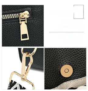 Detail of black pebbled leather texture with polished gold hardware and woven strap