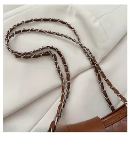 Detailed close-up of brown crocodile embossed texture and braided metal chain strap