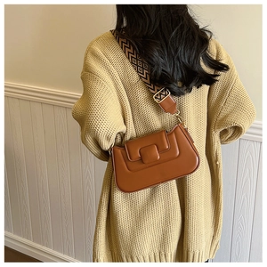 Modern brown PU leather crossbody bag with ethnic woven strap on a cozy knit cardigan