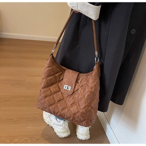 Close-up of a brown quilted hobo bag with a silver twist lock and minimalist shoulder strap