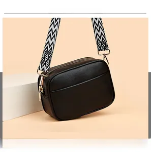 Detail of black pebbled leather camera bag with decorative black and white geometric strap
