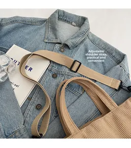 Detailed view of adjustable canvas shoulder strap on a khaki corduroy crossbody bag