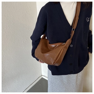 Detailed texture of dark brown vintage oil-finish leather on minimalist hobo shoulder bag