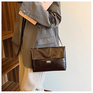 Detail view of coffee brown patent PU leather shoulder bag with silver chain and metal buckle