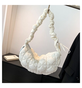 Close-up of white quilted crescent bag with textured puffy strap and silver zipper detail