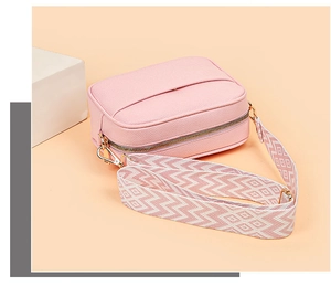 Detail showing pink pebble leather camera bag with wide colorful woven shoulder strap