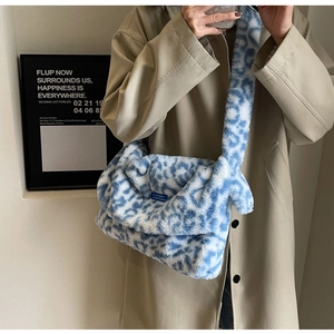 Detail of blue and white leopard faux fur crossbody bag worn with a beige trench coat