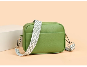 Detail view of grass green leather camera bag with wide geometric woven shoulder strap