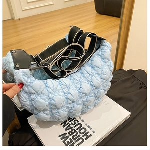 Dettaglio della borsa hobo celeste con trama trapuntata e tracolla in nylon a righe