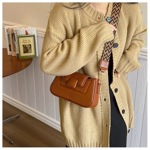 Detail view of brown PU leather handbag with geometric flap and wavy wide strap