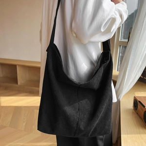 Dettaglio della texture in velluto a coste nero e della tracolla larga della borsa