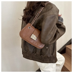 Detailed view of brown crocodile texture leather bag with silver chain strap and metal buckle