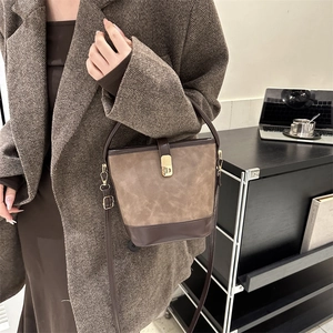 Braune Retro-Eimertasche aus Nubukleder mit Goldschloss am Modell im Wollmantel