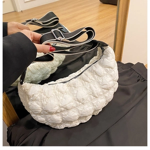 Dettaglio borsa a mezzaluna trapuntata bianca con design a sbuffo e tracolla bicolore larga