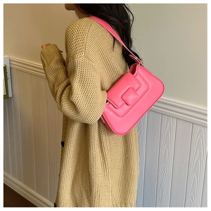 Detail view of pink PU leather baguette bag with square buckle worn with a beige cardigan