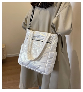 Close-up of white quilted shiny tote bag with side pockets and smooth nylon texture
