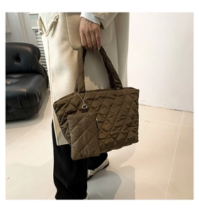 Detail of dark brown quilted nylon tote bag and matching mini pouch held by model