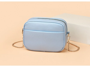 Detail view of light blue lychee pattern crossbody bag with gold chain strap and front pocket