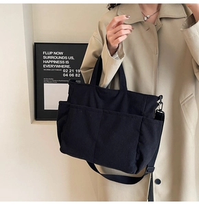 Detail of black corduroy tote bag showing vertical ribbed texture and utility pockets