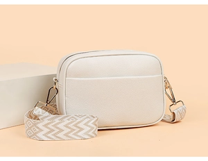Detail of off-white camera bag with lychee texture leather and geometric woven strap
