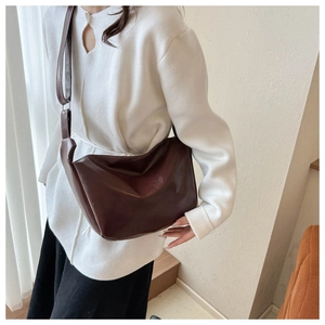 Deep brown retro PU crossbody bag with soft pleats and adjustable strap on a model